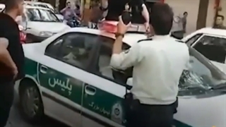 زنی که با نشستن بر روی سقف ماشین پلیس جنجال زیادی به پا کرد
